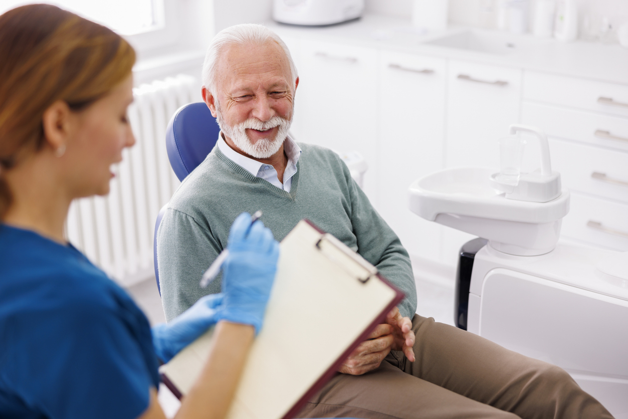 Implant dentist discussing fixed denture alternatives with a patient at consultation